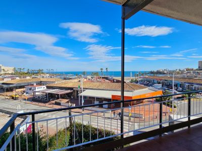 Vue depuis la terrasse sur une rue animée avec des commerces et des toits de tuiles traditionnels, s'étendant vers la plage de l'Arenal et la mer Méditerranée sous un ciel clair.