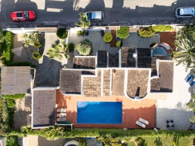 Vue aérienne de la villa privée avec piscine rectangulaire bleue, terrasse solarium en terre cuite et grand jardin arboré de plantes méditerranéennes et entrée pavée.