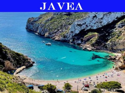 Vue aérienne d'une crique de Jávea avec des eaux turquoise et limpides, une plage de galets animée et des falaises rocheuses couvertes de végétation méditerranéenne.