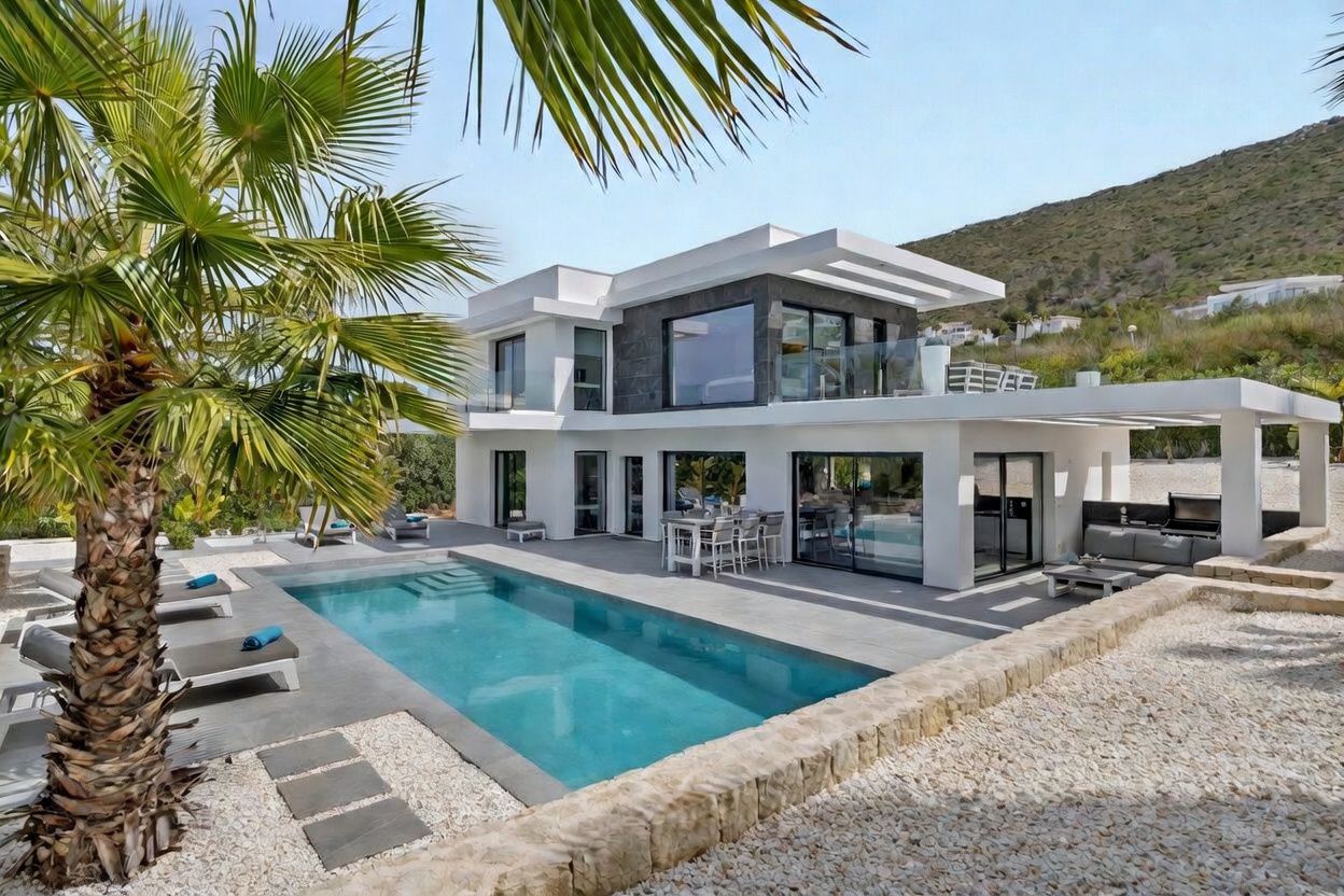 Extérieur de villa moderne avec piscine rectangulaire, salle à manger extérieure couverte et espace barbecue, encadrée par un palmier et des collines verdoyantes.