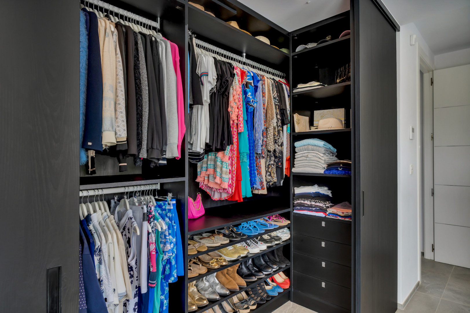 Grand dressing avec armoires en bois sombre grainé, tringles intégrées, étagères à chaussures étagées et tiroirs profonds pour une organisation optimale.