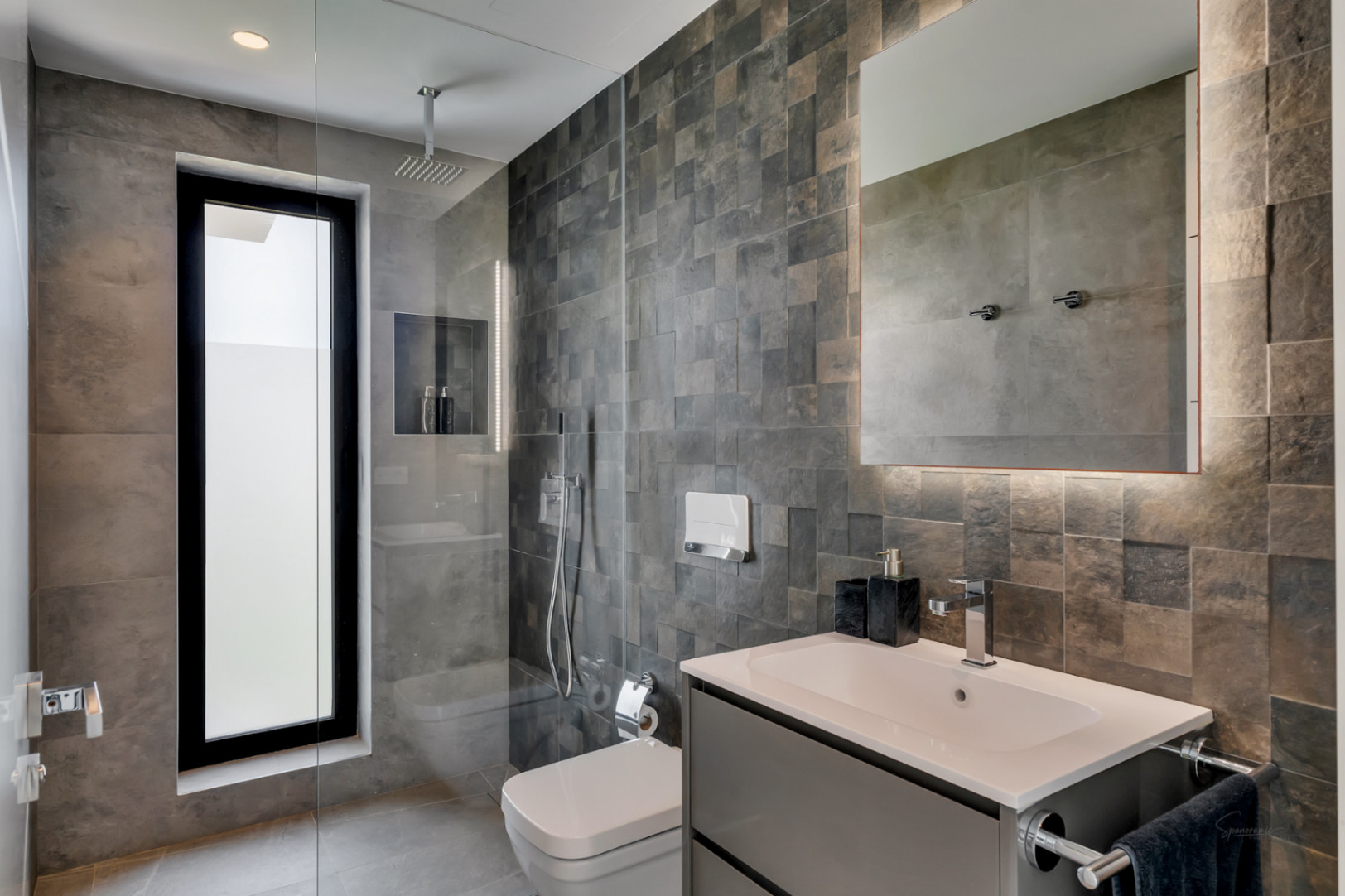 Salle de bain contemporaine avec douche à l'italienne, fenêtre verticale et carrelage gris texturé. Meuble-lavabo suspendu, vasque rectangulaire et miroir éclairé.