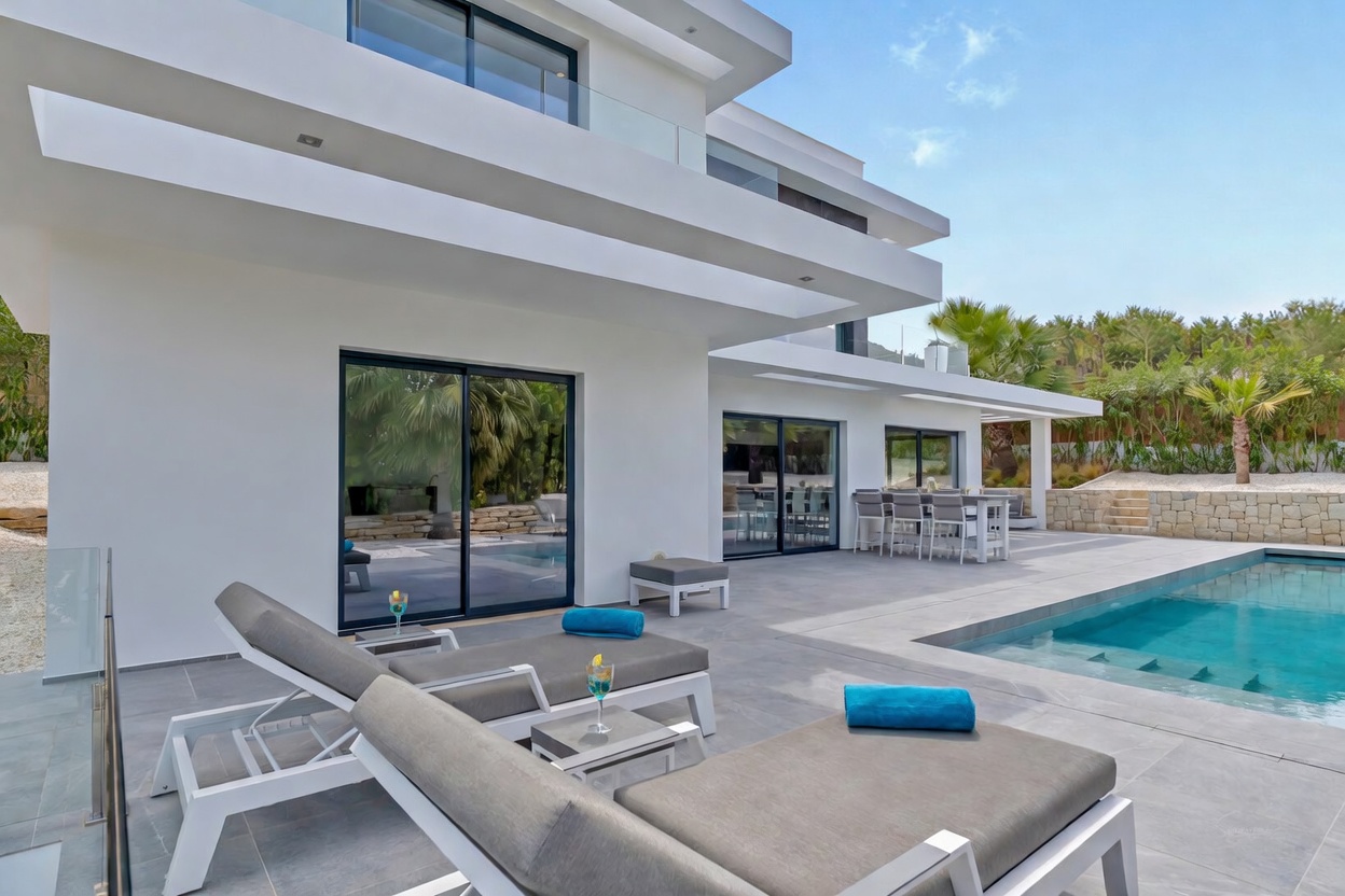Vaste terrasse extérieure de la villa moderne, comprenant une piscine rectangulaire, des chaises longues contemporaines et un espace repas élégant, accessible par de grandes baies vitrées.