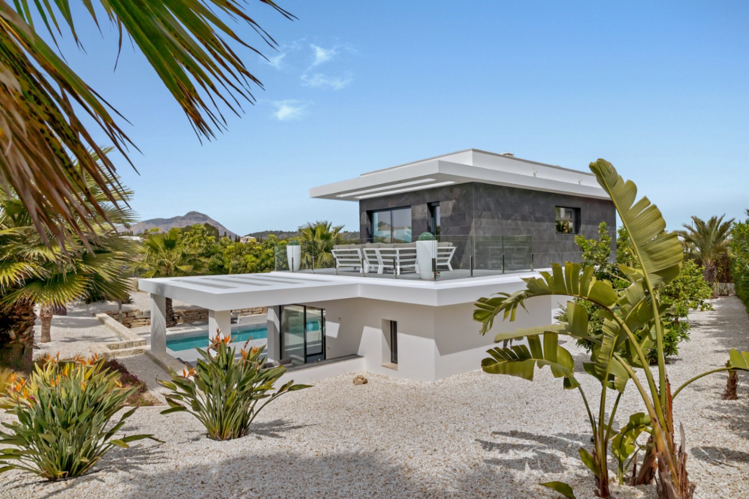 Vue de la piscine chauffée de 12x4 mètres avec sa couverture électrique intégrée, bordée de vastes terrasses et du jardin paysager.