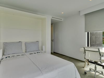 Chambre moderne avec lit mural intégré, bureau épuré près d'une fenêtre offrant une vue sur la piscine et carrelage gris.