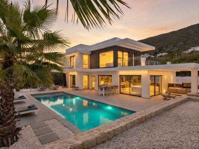 Piscine chauffée au design moderne avec couverture intégrée, entourée d'une terrasse en grès et d'un jardin méditerranéen facile d'entretien.