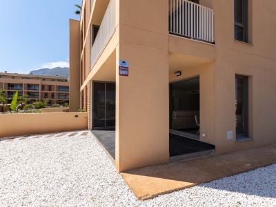 Extérieur de rez-de-chaussée avec façade ocre moderne. Il comprend un jardin privé en gravier blanc et une terrasse couverte avec accès direct à l'intérieur, vue sur la montagne.