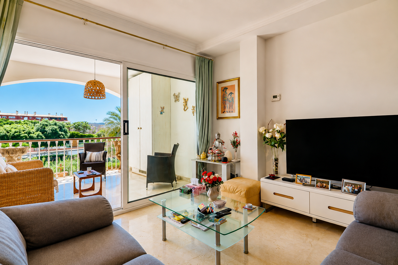 Lumineux salon avec sol effet marbre, s'ouvrant sur une terrasse privée aménagée de mobilier en osier et offrant des vues verdoyantes.