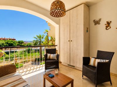 Vaste terrasse privée avec sol en marbre, mobilier en rotin et table en bois. Comprend un placard intégré et offre des vues sur la verdure et le ciel clair.