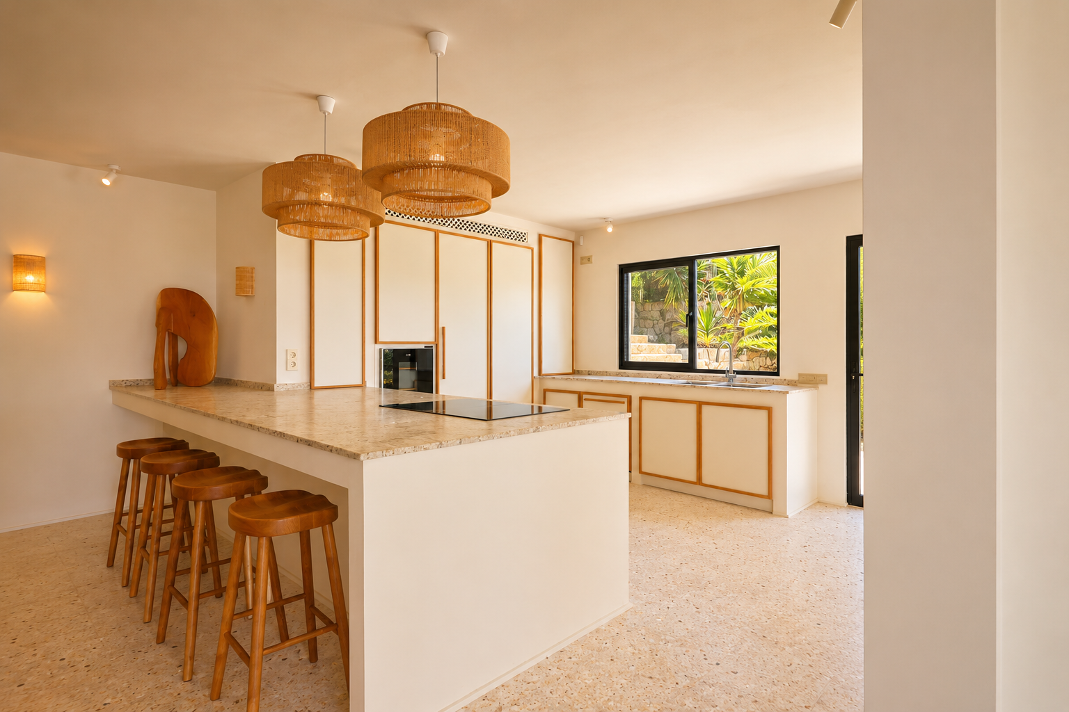 Îlot de cuisine moderne avec plaque de cuisson intégrée, comptoir clair moucheté et cinq tabourets en bois. Des suspensions tressées éclairent l'espace, offrant une vue sur la verdure luxuriante.
