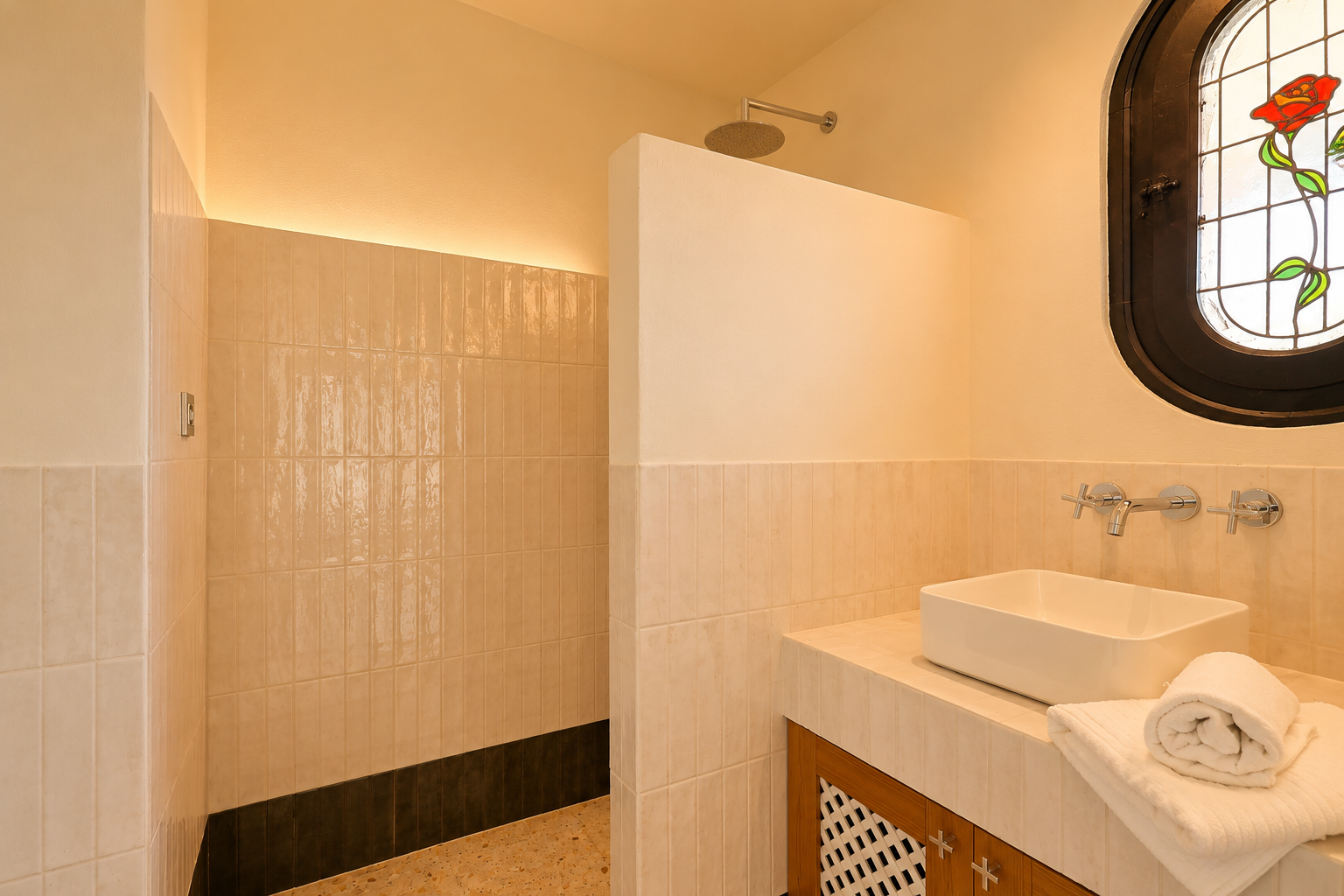 Salle de bain moderne avec douche à l'italienne, pommeau de pluie et éclairage LED indirect. Lavabo vasque sur meuble carrelé et fenêtre ovale en vitrail ornée d'une rose.