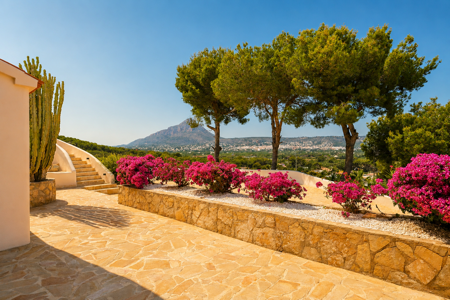 Terrasse extérieure avec pavé en pierre naturelle, escalier courbé et bougainvilliers éclatants. Un grand cactus et des vues panoramiques sur les montagnes et la ville.