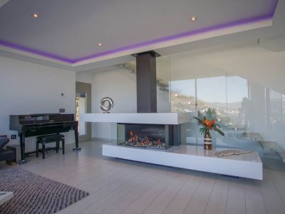 Le salon élégant est doté d'une cheminée à gaz transparente moderne, d'un piano à queue et d'un escalier en verre, avec vue sur la montagne.