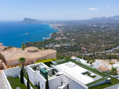 Vue aérienne de la terrasse sur le toit de la villa, dotée d'un escalier en colimaçon blanc, de gazon artificiel, de garde-corps en verre et de vues panoramiques sur la mer et la côte.