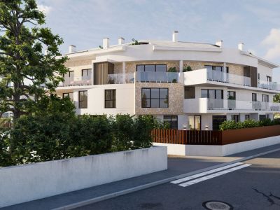 Immeuble d'appartements moderne à façade courbe, combinant stuc blanc et revêtement en pierre naturelle, avec balcons vitrés. La verdure méditerranéenne encadre la propriété.