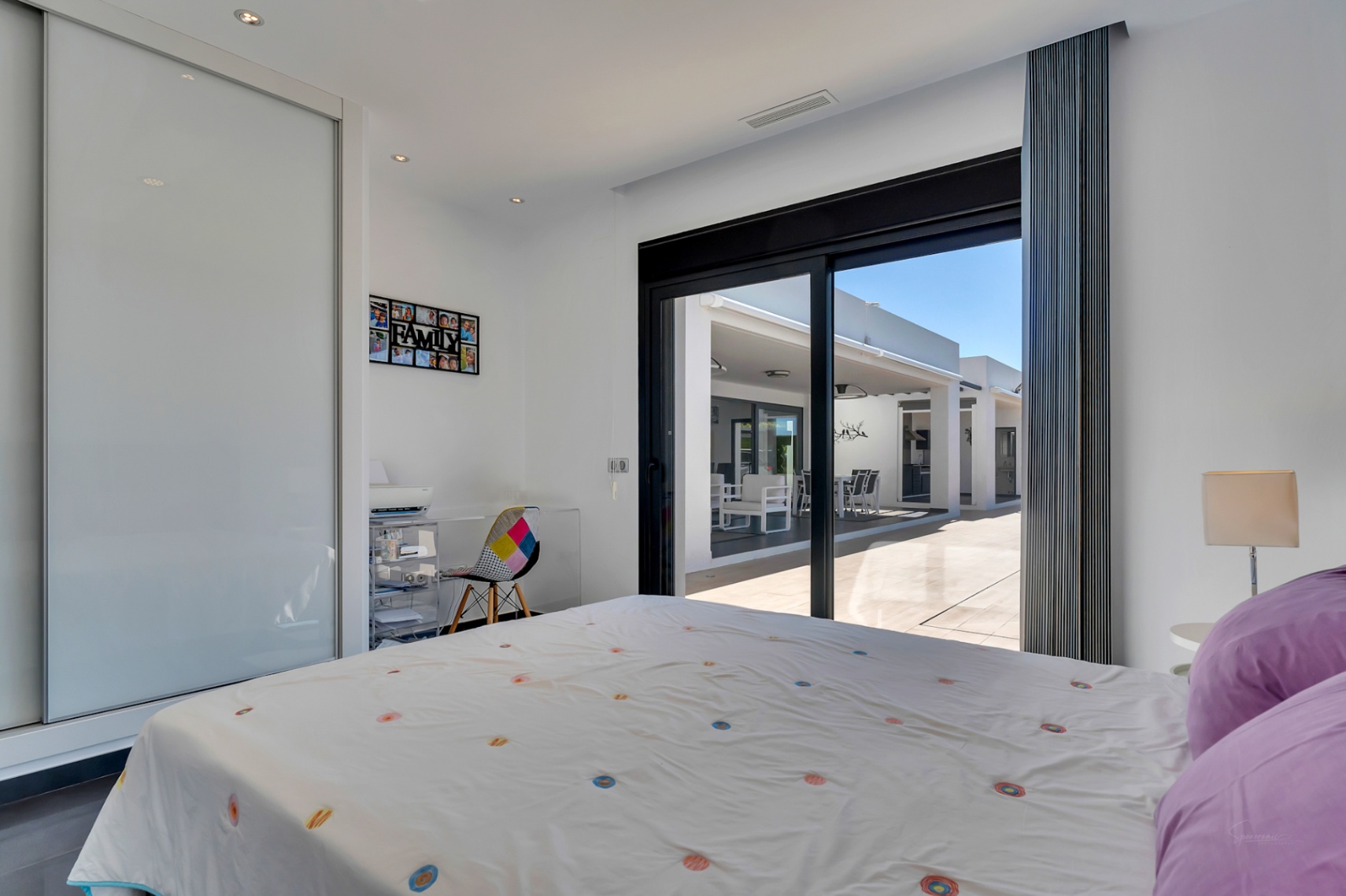 Chambre lumineuse avec accès direct à la terrasse, dotée d'une armoire intégrée à portes coulissantes et d'un coin bureau pratique.