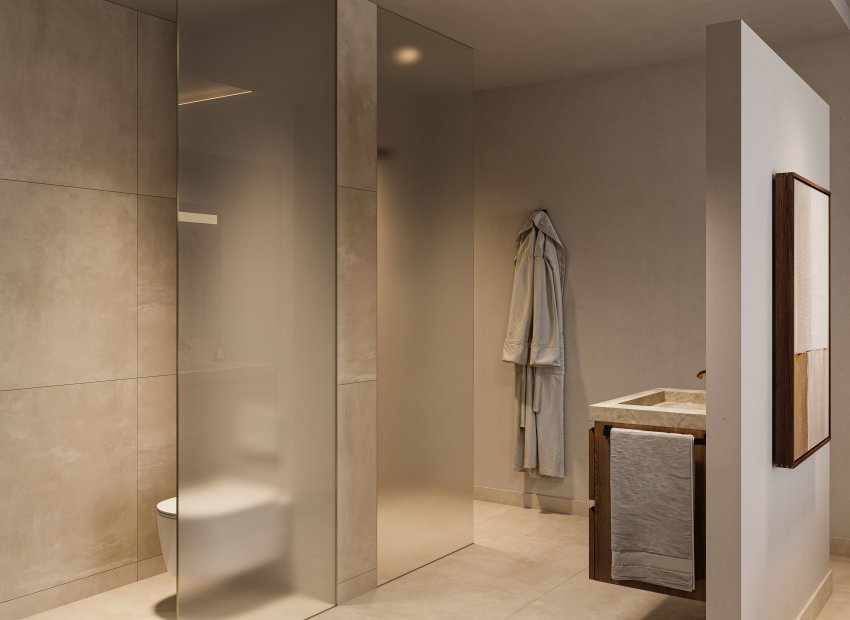 Salle de bain moderne avec une cloison en verre dépoli pour les toilettes, un lavabo en pierre sur une vanité en bois foncé et de grands carreaux aux tons neutres. L'éclairage encastré souligne le design épuré.