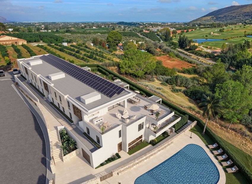 Vue aérienne d'une résidence de luxe moderne avec panneaux solaires sur le toit, terrasses extérieures avec salons et salles à manger, et une grande piscine, entourée d'un golf et de vergers.