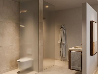 Salle de bain moderne avec une cloison en verre dépoli pour les toilettes, un lavabo en pierre sur une vanité en bois foncé et de grands carreaux aux tons neutres. L'éclairage encastré souligne le design épuré.