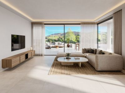 Salon moderne avec canapé d'angle neutre, table basse ovale et meuble TV suspendu en bois. Les baies vitrées mènent à une terrasse spacieuse avec vues panoramiques sur les collines verdoyantes.