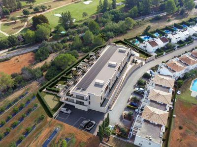 Vue aérienne d'un bâtiment moderne avec toit solaire et une vaste terrasse paysagée comprenant des pergolas, des sièges extérieurs et un putting green, adossé à un parcours de golf.