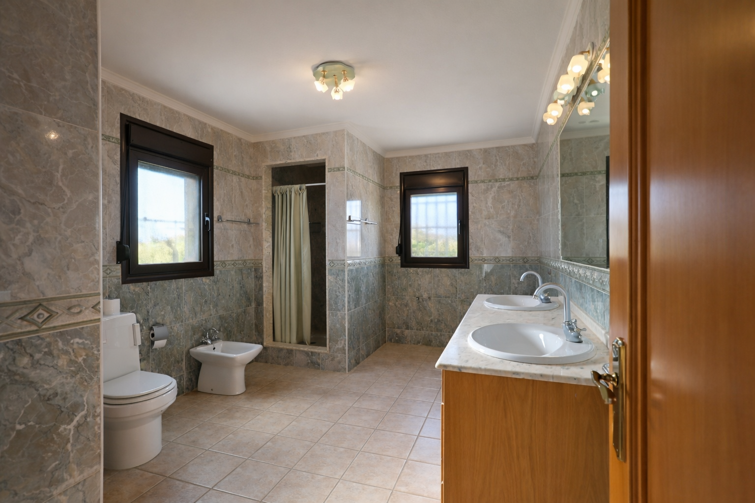 Salle de bain spacieuse avec double vasque sur plan de travail en marbre et meuble en bois. Elle comprend une douche à l'italienne, des toilettes, un bidet et deux fenêtres. Salle de bain spacieuse avec double vasque sur plan de travail en marbre et meuble en bois. Elle comprend une douche à l'italienne, des toilettes, un bidet et deux fenêtres.