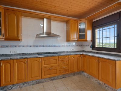 Cuisine aménagée avec des meubles en bois, des plans de travail en granit et un plafond en lattes de bois. Fenêtre grillagée avec vue extérieure.