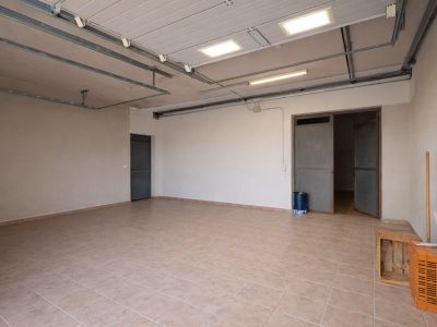 Grand garage ou espace utilitaire avec carrelage clair, éclairage de plafond industriel et multiples points d'accès.