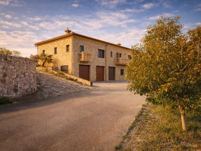 L'extérieur en pierre de la finca comprend trois garages intégrés et d'élégants balcons, accessible par une allée pavée et un mur de pierre incurvé.