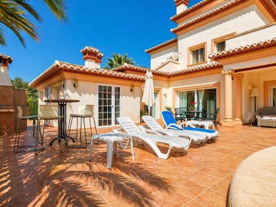 Vaste terrasse extérieure en terre cuite, équipée de chaises longues et d'un espace barbecue intégré, avec accès direct à la villa.