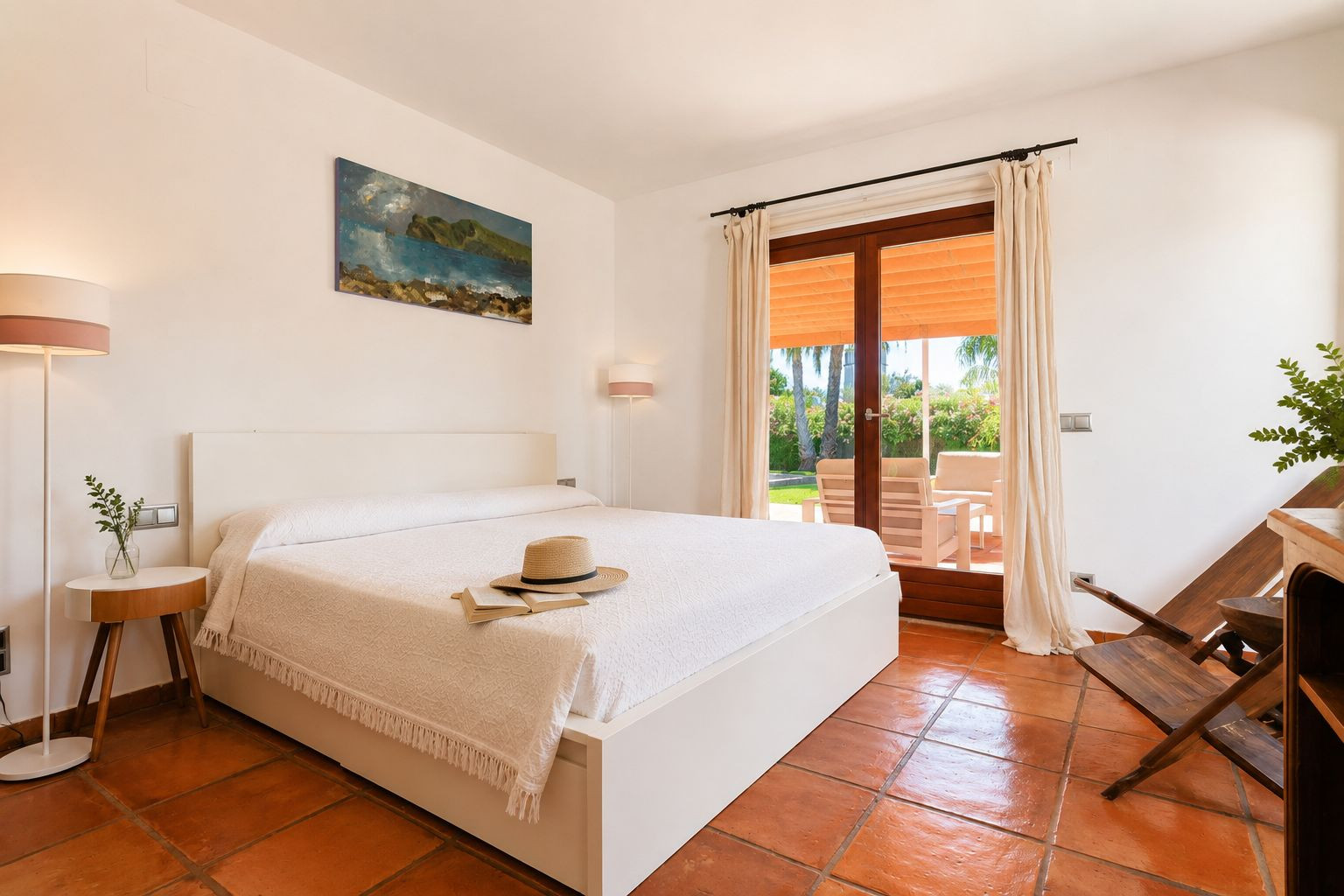 Chambre lumineuse avec lit blanc, sols en terre cuite artisanale et accès direct à une terrasse extérieure offrant vue sur le jardin. Chambre lumineuse avec lit blanc, sols en terre cuite artisanale et accès direct à une terrasse extérieure offrant vue sur le jardin.
