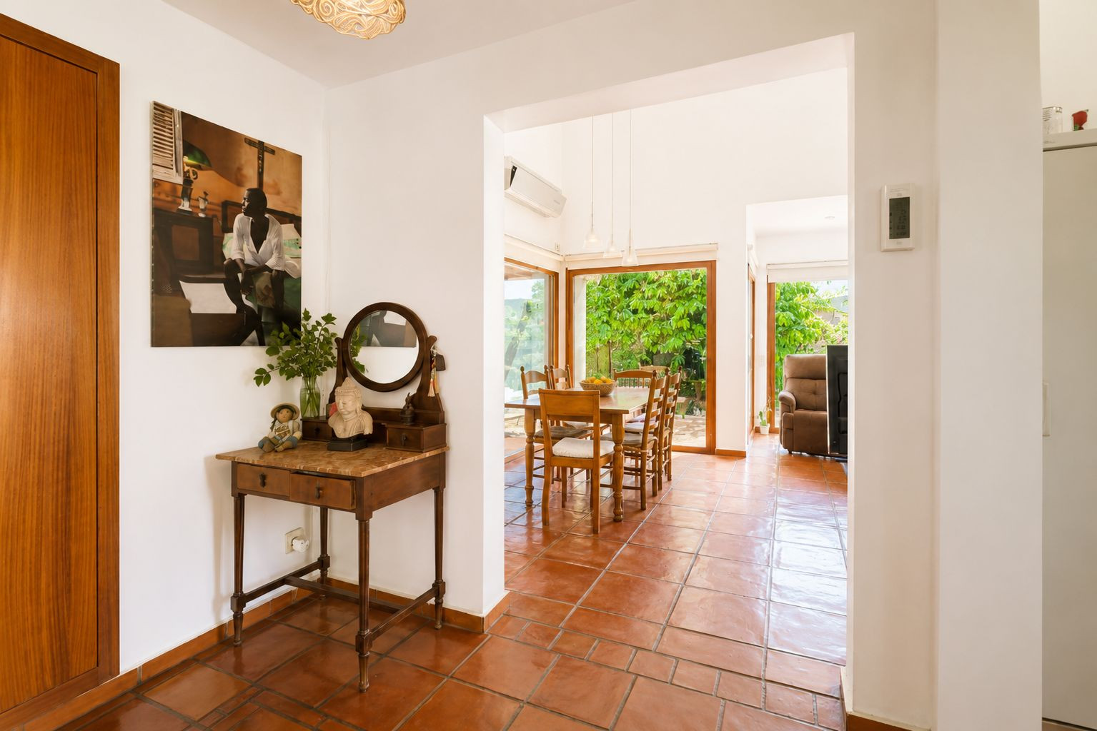 L'entrée lumineuse, avec son sol en terre cuite et sa console vintage, mène à une salle à manger spacieuse dotée de grandes fenêtres donnant sur le jardin luxuriant. L'entrée lumineuse, avec son sol en terre cuite et sa console vintage, mène à une salle à manger spacieuse dotée de grandes fenêtres donnant sur le jardin luxuriant.