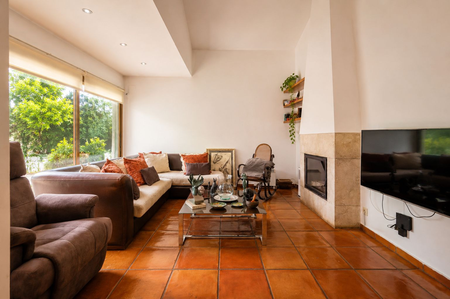 Lumineux salon avec sols en terre cuite artisanale, cheminée en pierre et grandes fenêtres offrant une vue sur la végétation luxuriante. Lumineux salon avec sols en terre cuite artisanale, cheminée en pierre et grandes fenêtres offrant une vue sur la végétation luxuriante.