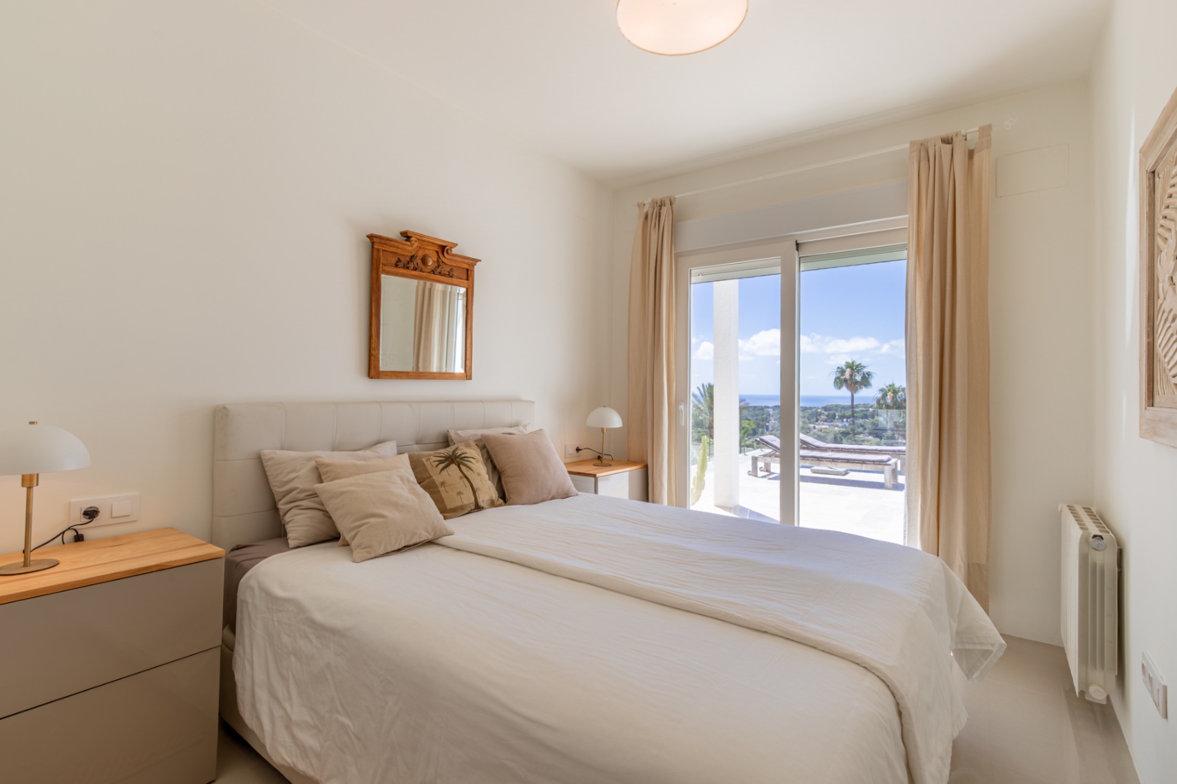 Chambre lumineuse avec lit, tables de chevet et accès direct à une terrasse offrant une vue panoramique sur la mer et des chaises longues. Chambre lumineuse avec lit, tables de chevet et accès direct à une terrasse offrant une vue panoramique sur la mer et des chaises longues.