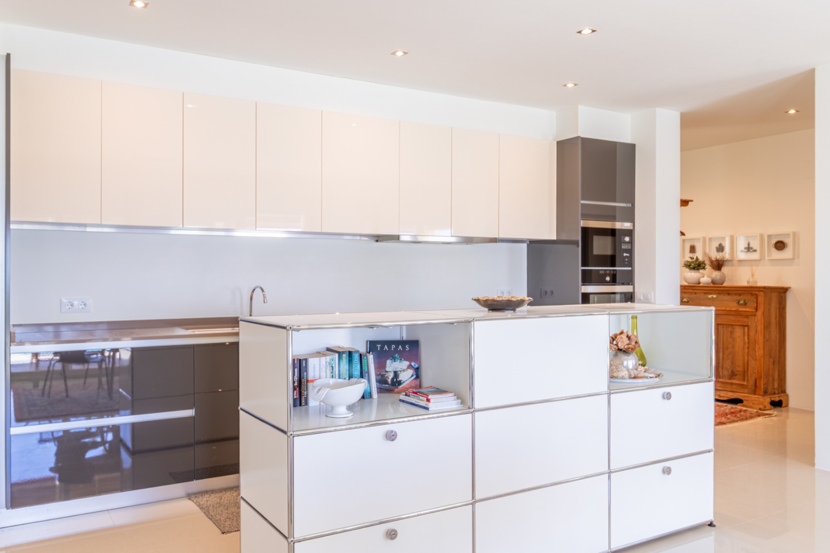 Cuisine moderne avec meubles hauts laqués beige clair et bas gris foncé. Îlot central intégrant rangements ouverts et électroménagers encastrés. Cuisine moderne avec meubles hauts laqués beige clair et bas gris foncé. Îlot central intégrant rangements ouverts et électroménagers encastrés.