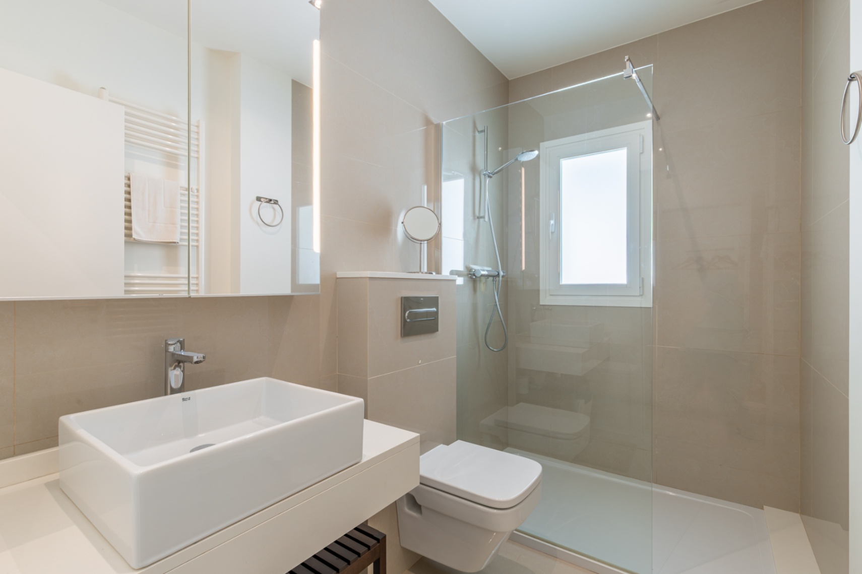 Salle de bain contemporaine avec lavabo rectangulaire, WC suspendu et douche à l'italienne vitrée. Carrelage neutre et miroir éclairé par LED verticale définissent l'espace. Salle de bain contemporaine avec lavabo rectangulaire, WC suspendu et douche à l'italienne vitrée. Carrelage neutre et miroir éclairé par LED verticale définissent l'espace.
