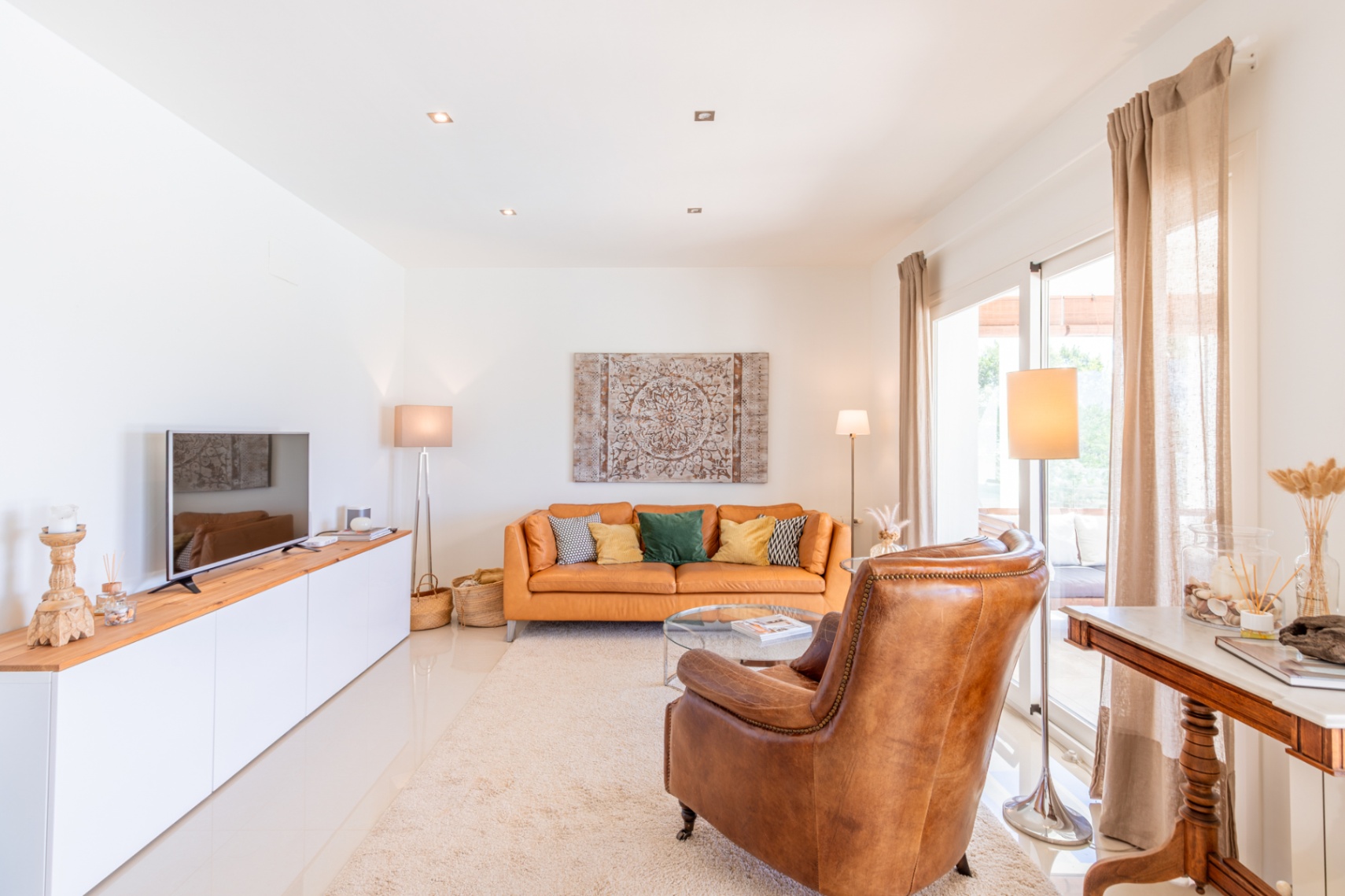 Salon lumineux avec un canapé en cuir couleur terre de Sienne, un fauteuil et un meuble TV. Des portes coulissantes vitrées mènent à l'extérieur. Salon lumineux avec un canapé en cuir couleur terre de Sienne, un fauteuil et un meuble TV. Des portes coulissantes vitrées mènent à l'extérieur.