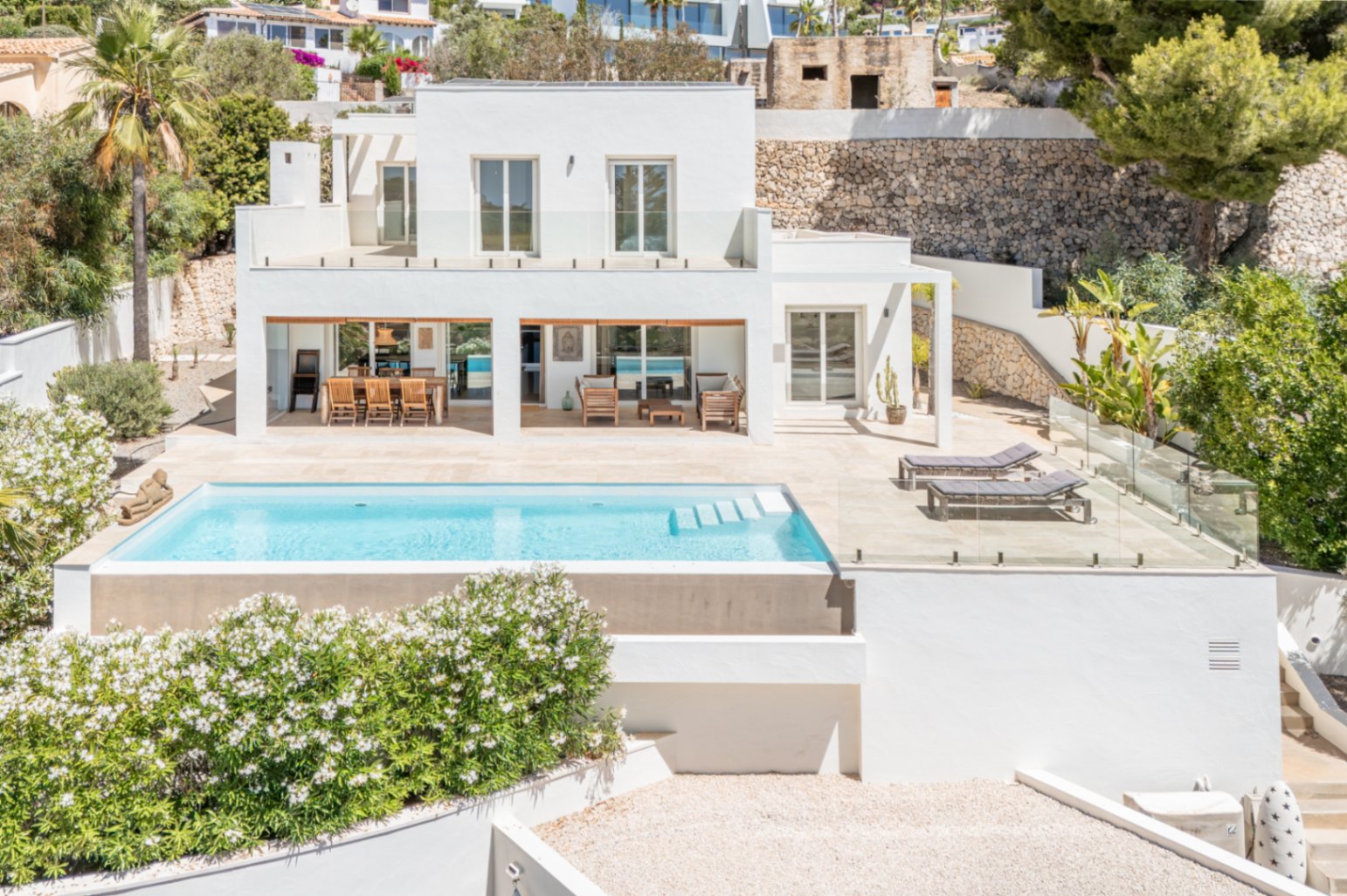 Villa moderne à deux étages avec piscine rectangulaire et grande terrasse carrelée. Comprend un espace repas extérieur couvert et une balustrade en verre, intégrant le design au paysage méditerranéen. Villa moderne à deux étages avec piscine rectangulaire et grande terrasse carrelée. Comprend un espace repas extérieur couvert et une balustrade en verre, intégrant le design au paysage méditerranéen.