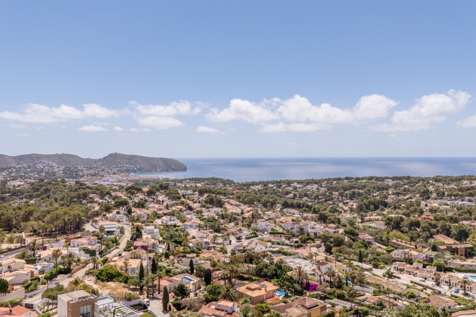 Vue aérienne panoramique d'une zone résidentielle côtière, avec des toits en terre cuite, une végétation luxuriante et la mer Méditerranée à l'horizon. Vue aérienne panoramique d'une zone résidentielle côtière, avec des toits en terre cuite, une végétation luxuriante et la mer Méditerranée à l'horizon.