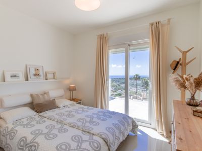 Chambre lumineuse à l'étage avec accès terrasse, offrant une vue panoramique sur la mer Méditerranée. Meubles en bois clair et carrelage au sol.