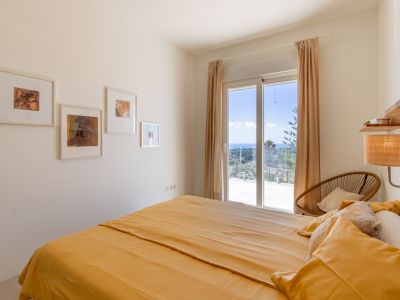Chambre lumineuse avec lit double et accès direct à une terrasse. Elle offre une vue panoramique sur la mer Méditerranée via une grande porte coulissante.