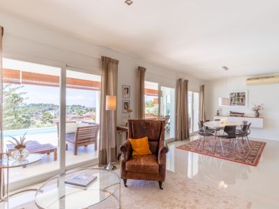 Salon-salle à manger ouvert avec de grandes baies vitrées donnant sur la terrasse, la piscine et le paysage. Carrelage blanc brillant et mobilier moderne.