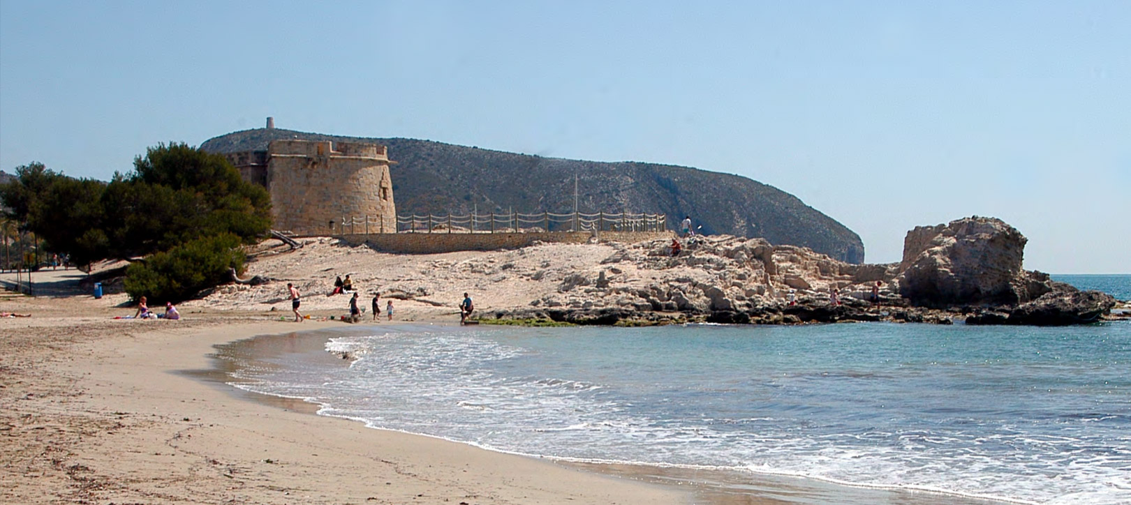 Plage de sable avec une tour de guet historique en pierre sur un promontoire rocheux, bordée par les eaux calmes de la Méditerranée sous un ciel clair. Plage de sable avec une tour de guet historique en pierre sur un promontoire rocheux, bordée par les eaux calmes de la Méditerranée sous un ciel clair.