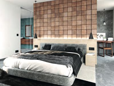 Chambre moderne avec mur d'accent carrelé derrière le lit gris rembourré et éclairage intégré. Un coin bureau et une salle de bain attenante aux carreaux turquoise sont visibles.