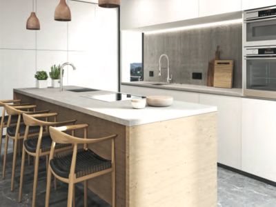 Cuisine contemporaine avec îlot en béton clair intégrant plaque et évier, tabourets de bar en bois et meubles blancs sans poignées. Éclairage encastré sur la crédence en béton.