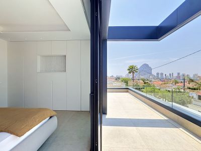 Chambre moderne avec placards intégrés blancs et accès direct à une terrasse spacieuse. Vues panoramiques sur Calpe et le majestueux Peñón de Ifach.