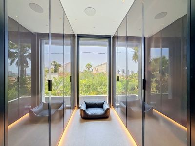 Dressing épuré avec placards miroirs toute hauteur, éclairage de sol intégré et grande fenêtre offrant une vue sur la verdure tropicale.