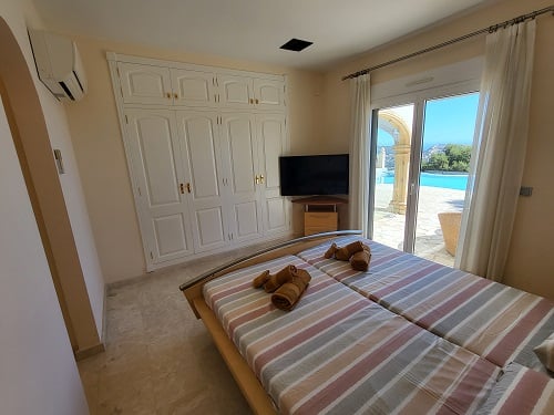Chambre avec lits jumeaux, placard intégré et accès direct à la piscine. Équipée d'une télévision et de la climatisation, elle offre une vue sur l'extérieur.