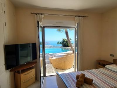 Chambre lumineuse avec lits jumeaux et télévision, s'ouvrant directement sur une terrasse. Profitez des vues imprenables sur la piscine à débordement et la mer Méditerranée.