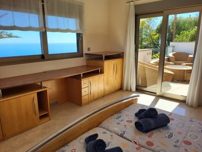 Chambre lumineuse avec lits jumeaux, un bureau en bois intégré et une vue imprenable sur la mer. Accès direct à une terrasse privée aménagée.